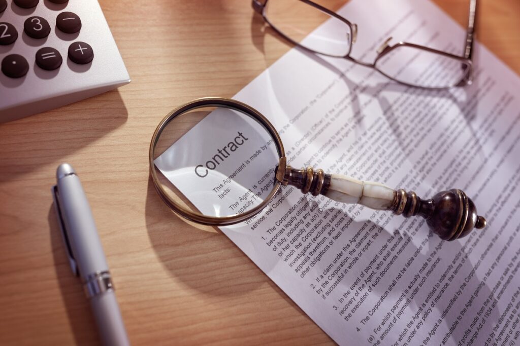 Close-up of magnifying glass examining contractual clauses on legal construction document